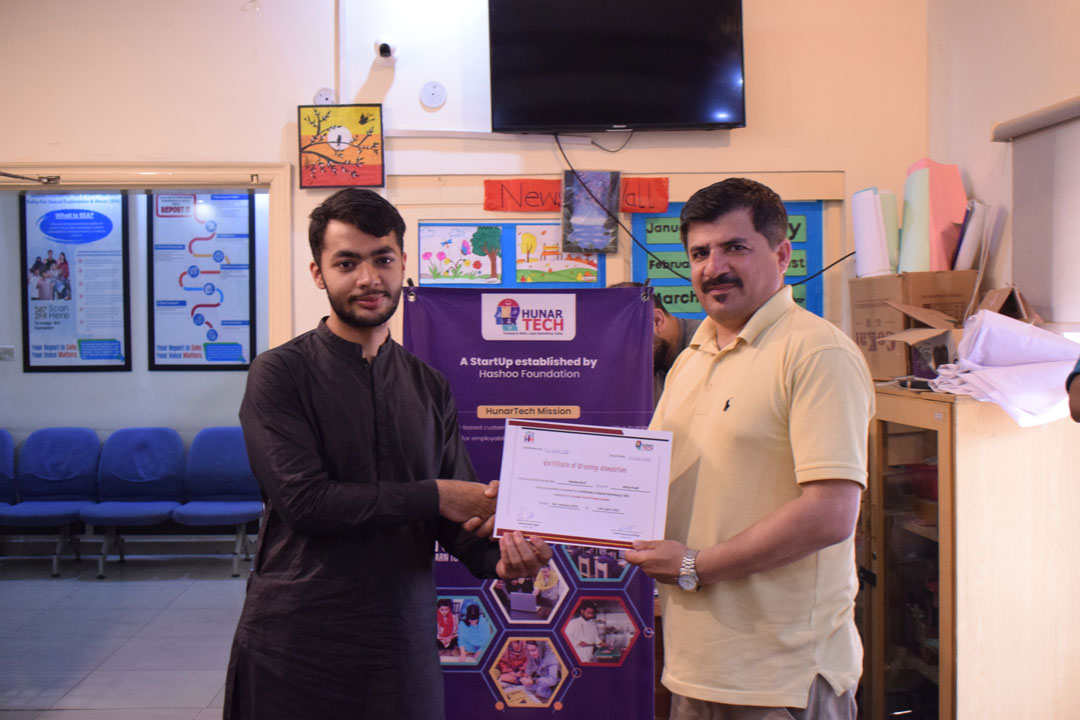 A student receives a certificate from an instructor during the certificate distribution ceremony of the Digital Marketing and SEO course at Hunar Tech Rawalpindi.